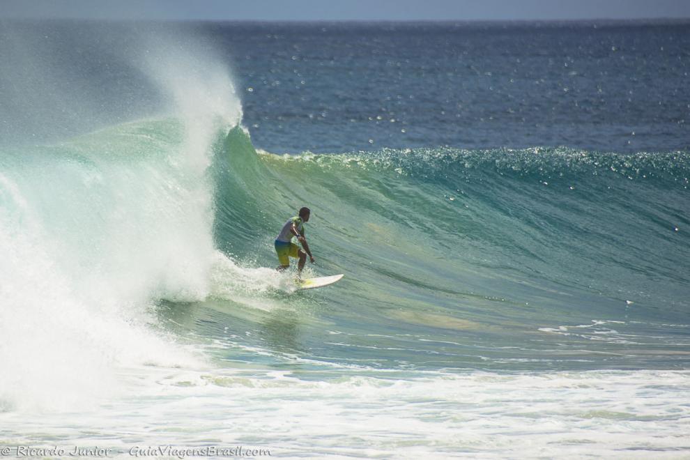 Imagem de um surfista com vento no mar azul maravilhoso de Noronha.
